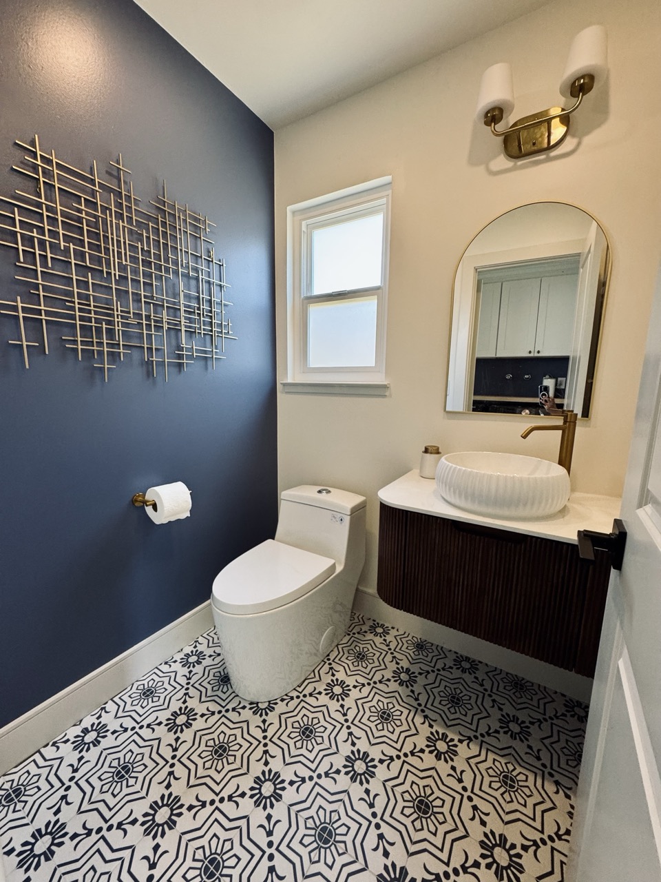 Powder room after remodel with navy wall and patterned tile