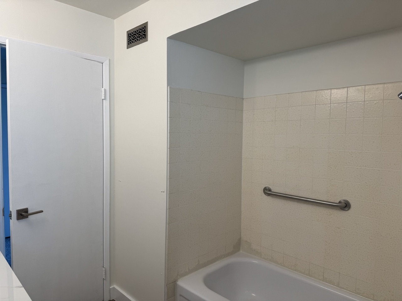 Guest bathroom before remodel with dated tile and grab bars