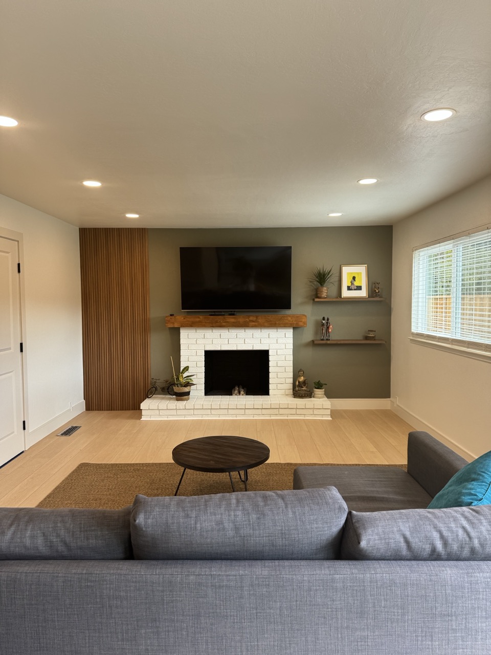 Family room after remodel with white fireplace and slatted wood wall