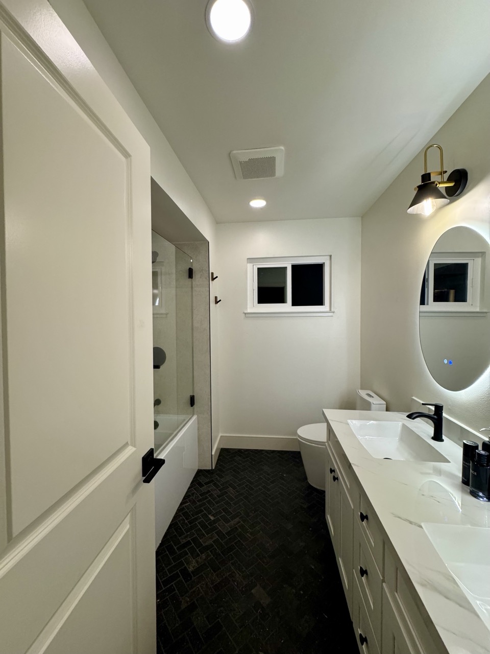 Guest bath after — wide view of vanity, toilet, and shower